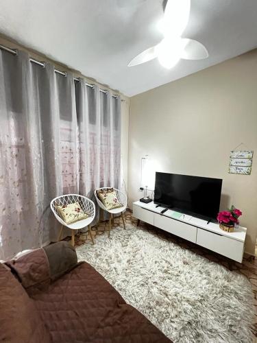 a living room with a flat screen tv and two chairs at Divino Espírito Santo in Aparecida