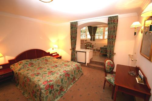 a hotel room with a bed and a desk at Park Hotel am Schloss in Ettringen