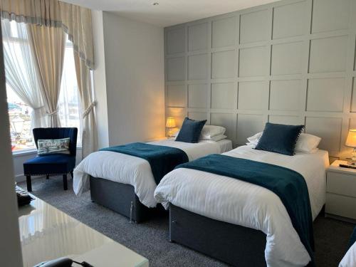 ein Hotelzimmer mit 2 Betten und einem Stuhl in der Unterkunft Revelstoke Hotel in Bridlington