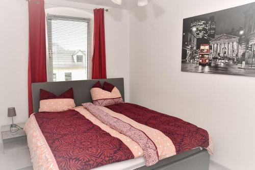 Un dormitorio con una cama con sábanas rojas y una ventana en Ferienapartment-Loebau-Stadt-und-Messenah en Löbau