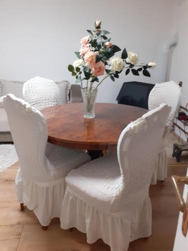 een houten tafel met witte stoelen en een vaas met bloemen bij BELA VILA MIJALKOV 