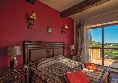 a bedroom with a bed with red walls and a window at LeVecca Village House 1 - Gladiola in Għasri