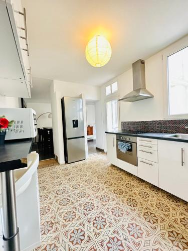 une grande cuisine avec des placards blancs et une cuisinière dans l'établissement Reims Sherpa Lodge, à Reims