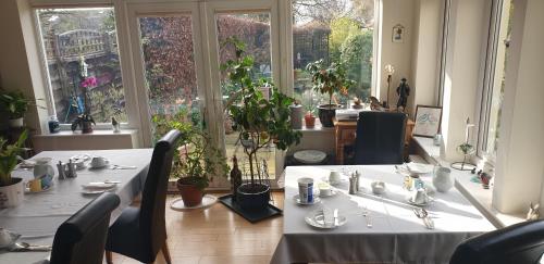 uma sala de jantar com duas mesas e cadeiras e janelas em Ugiebrae House Bed & Breakfast em Seahouses