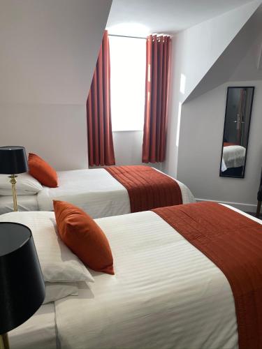a hotel room with three beds with red curtains at Revelstoke Hotel in Bridlington