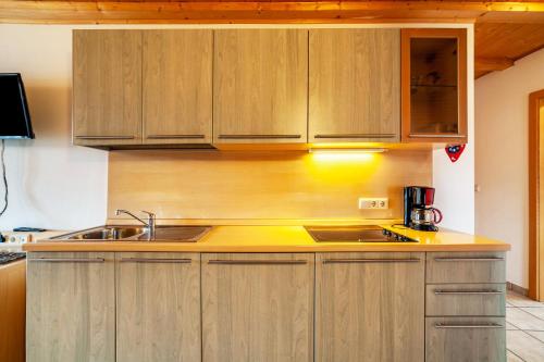 a kitchen with wooden cabinets and a sink at Lingerhof Alpenrose in Meltina