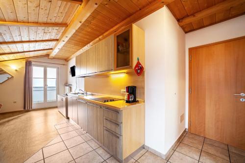 a large kitchen with wooden ceilings and wooden cabinets at Lingerhof Alpenrose in Meltina