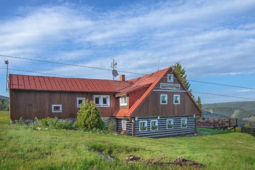 a barn with a red roof on top of a field at Sagasserovy boudy U Dvou vleků in Pec pod Sněžkou