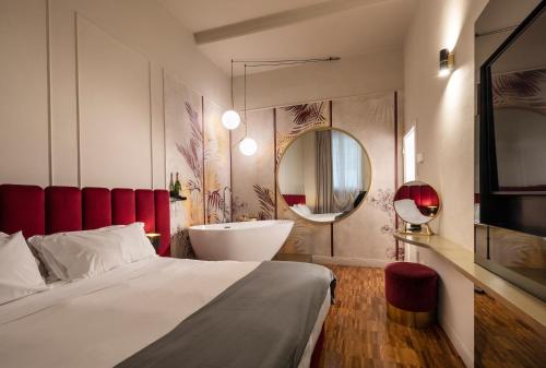 a bedroom with a bed and a tub and a mirror at Ricasoli Garden Relais in Florence