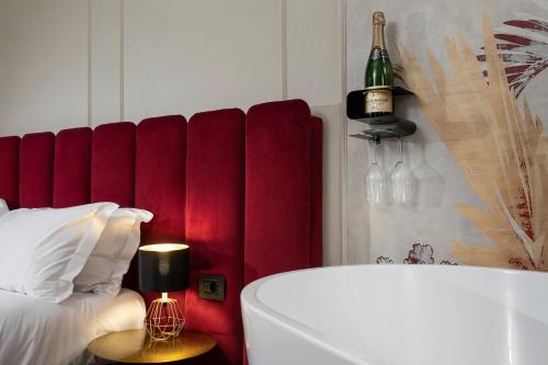 a bedroom with a red headboard and a bottle of wine at Ricasoli Garden Relais in Florence