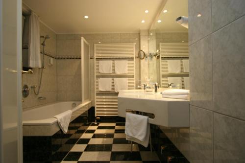 a bathroom with a tub and a sink and a bath tub at Park Hotel am Schloss in Ettringen