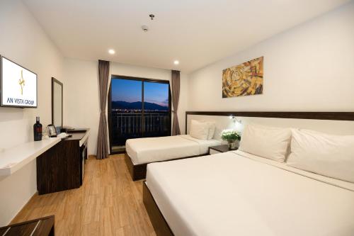 a hotel room with two beds and a window at An Vista Hotel in Nha Trang