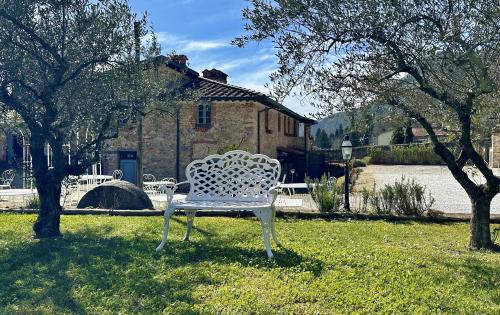 a white bench sitting in the grass in front of a building at La Sosta in Toscana in Camaiore