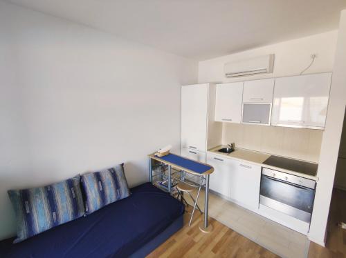 a small kitchen with a blue couch in a room at Sea view & pool studio by Pag tours in Pag