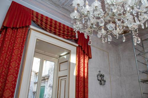 a chandelier in a room with red curtains and a mirror at Le Stanze Del Vicerè Boutique Hotel in Naples