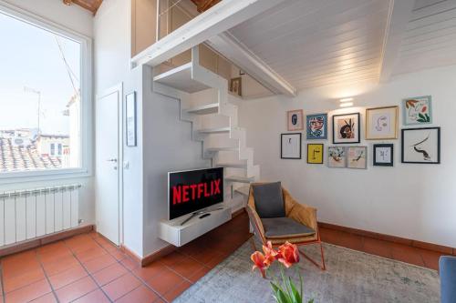 a living room with a tv and a staircase at [View of Pitti Palace] Elegant Loft in Florence