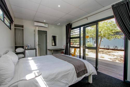 a bedroom with a large white bed and a balcony at SleepOver Beitbridge in Musina