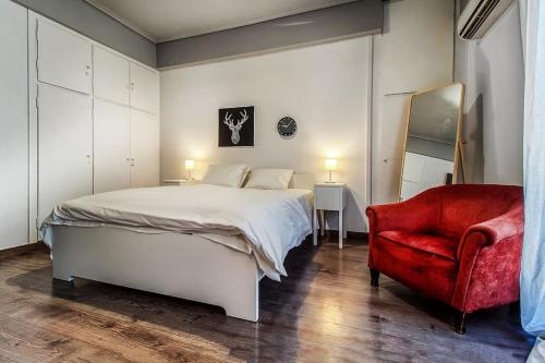 1 dormitorio con 1 cama blanca y 1 silla roja en Beautiful and cozy studio next to Athens center, en Atenas