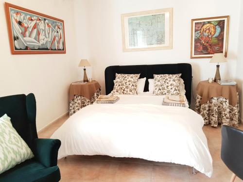 a bedroom with a white bed and a green chair at CASA DEL ARTISTA-CAN ROCA in Alcudia