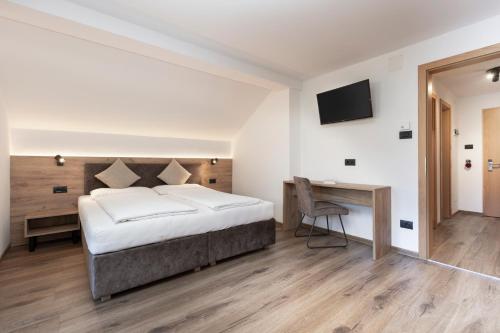 a bedroom with a bed and a desk and a television at Aparthotel Familiaris - Family Apartments - Pools & Spa in Dolomites in Valdaora