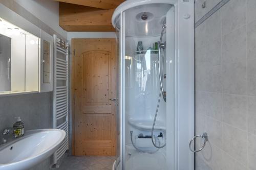 ein Bad mit einer Dusche und einem Waschbecken in der Unterkunft DolomiApartments - Appartamento Coronelle in Predazzo
