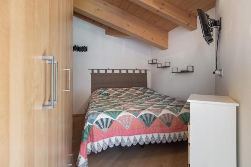 ein Schlafzimmer mit einem Bett mit einer Decke darauf in der Unterkunft DolomiApartments - Appartamento Coronelle in Predazzo