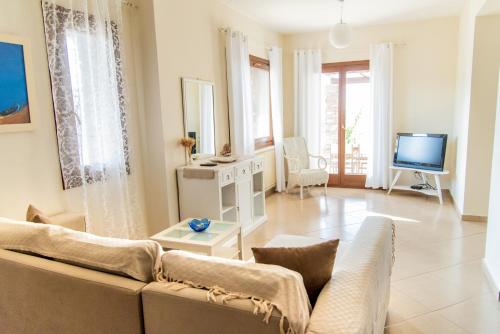 a living room with a couch and a tv at Villa Cavo d' Oro in Korissia