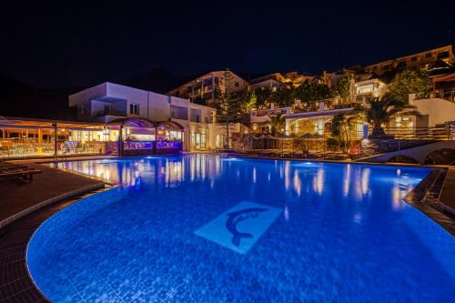 a large swimming pool at night at Elounda Residence Resort & Waterpark in Elounda