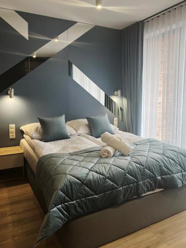 ノヴィ・タルクにあるAMSTERDAM - nowy apartament w centrum z prywatnym zadaszonym parkingiemの青い壁のベッドルーム1室(大型ベッド1台付)