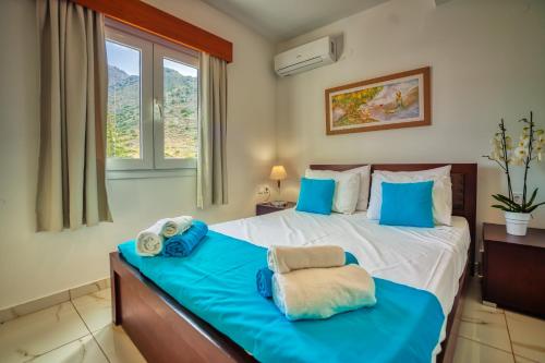 a bedroom with a large bed with blue pillows at Elounda Residence Resort & Waterpark in Elounda