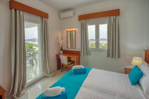 a bedroom with a bed and a desk and windows at Elounda Water Park Residence Hotel in Elounda