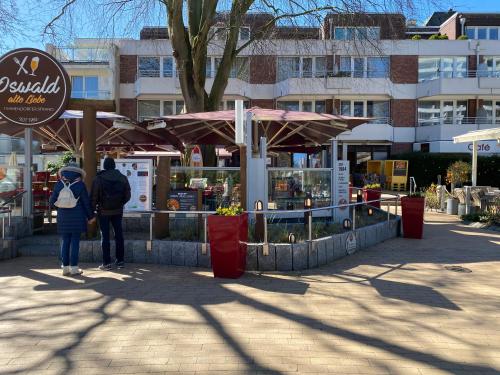 two people standing in front of a market with umbrellas at Modernes Apartment an Timmendorfer Promenade, 1. Reihe in Timmendorfer Strand
