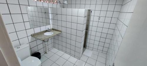 a white tiled bathroom with a toilet and a sink at Floripa Hostel in Florianópolis