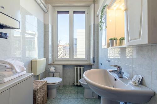 ein Bad mit einem Waschbecken, einem WC und einem Fenster in der Unterkunft Virginia Apartments in Parma