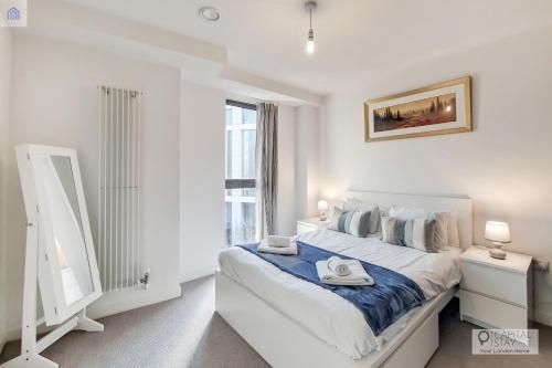 a white bedroom with a bed and a window at Deluxe One Bed Apartment by London ExCeL in London