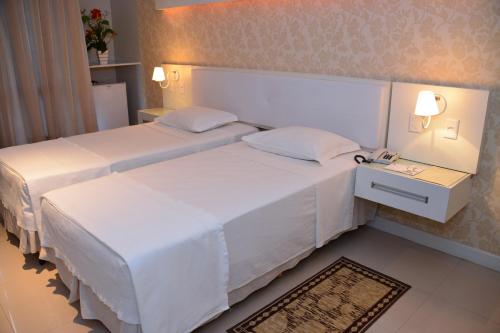 a hotel room with two beds and a night stand at Bahiamar Hotel in Salvador