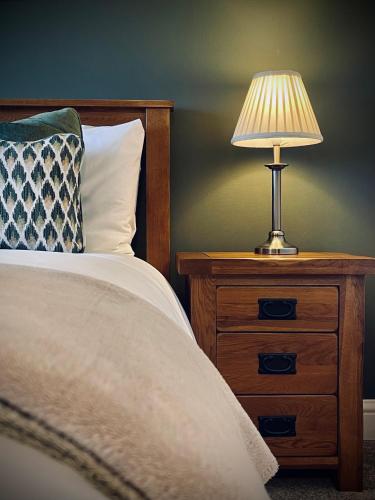 a bed with a night stand with a lamp on it at The Crown Inn in Rodmarton