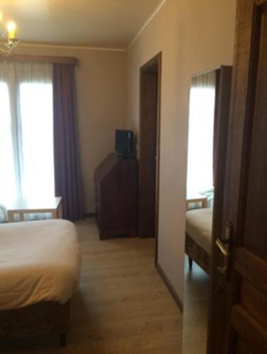 a hotel room with a bed and two windows at Hotel La Venerie in Virton