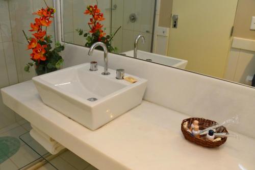 a bathroom with a sink and a mirror and flowers at Bahiamar Hotel in Salvador