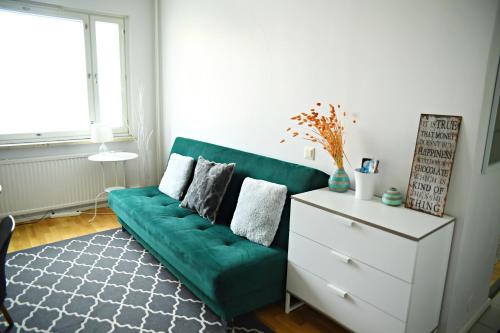 sala de estar con sofá verde y cómoda blanca en Scandinavian Modern home 34 1BR City Center in Kamppi Työmiehenkatu, en Helsinki