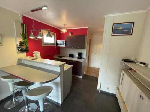 une cuisine avec des murs rouges et une table et des chaises dans l'établissement Studio calme à 2 pas de la plage avec balcon et garage - FR-1-550-17, à Saint-Georges-de-Didonne