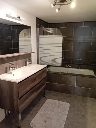 une salle de bain avec un lavabo, une baignoire et un miroir dans l'établissement Maison de ville, à Saint-Nazaire-dʼAude