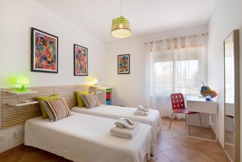 a bedroom with two beds and a desk and a chair at Mare Cheia in Santa Luzia