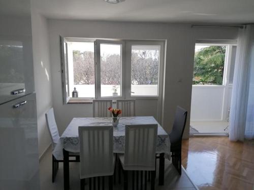 a dining room with a table with chairs and two windows at Sunny spot in Pula