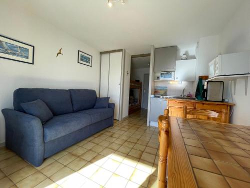 un salon avec un canapé bleu et une cuisine dans l'établissement Studio Centre-St Palais avec Terrasse et Garage, Proche Plages et Attractions - FR-1-550-28, à Saint-Palais-sur-Mer