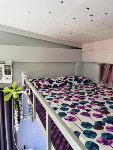 a bedroom with a bed with purple and blue flowers at JC Unit #8 in Urdaneta