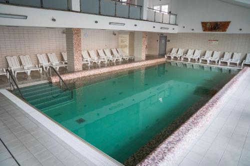 a large swimming pool with chairs in a building at Ceremoniár in Poľný Kesov