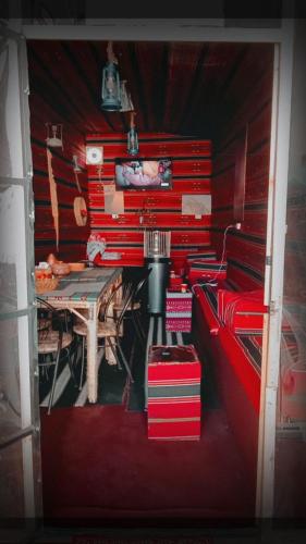 a room with a table and a red wall at Its your choice hostel in Wadi Musa