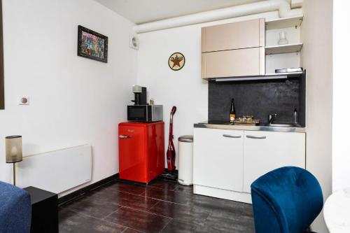 a kitchen with a red refrigerator and white cabinets at Charmant Studio à Neuilly-sur-Marne in Neuilly-sur-Marne