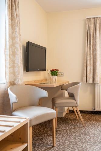 a room with a table and chairs and a television at Kirchenwirt in Strobl